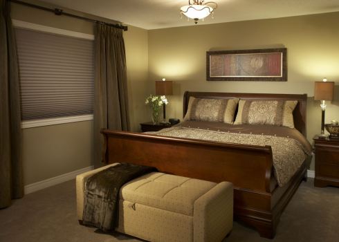 Luxury bedding, custom draperies, ample bench and pretty lighting create a haven in this transitional bedroom.